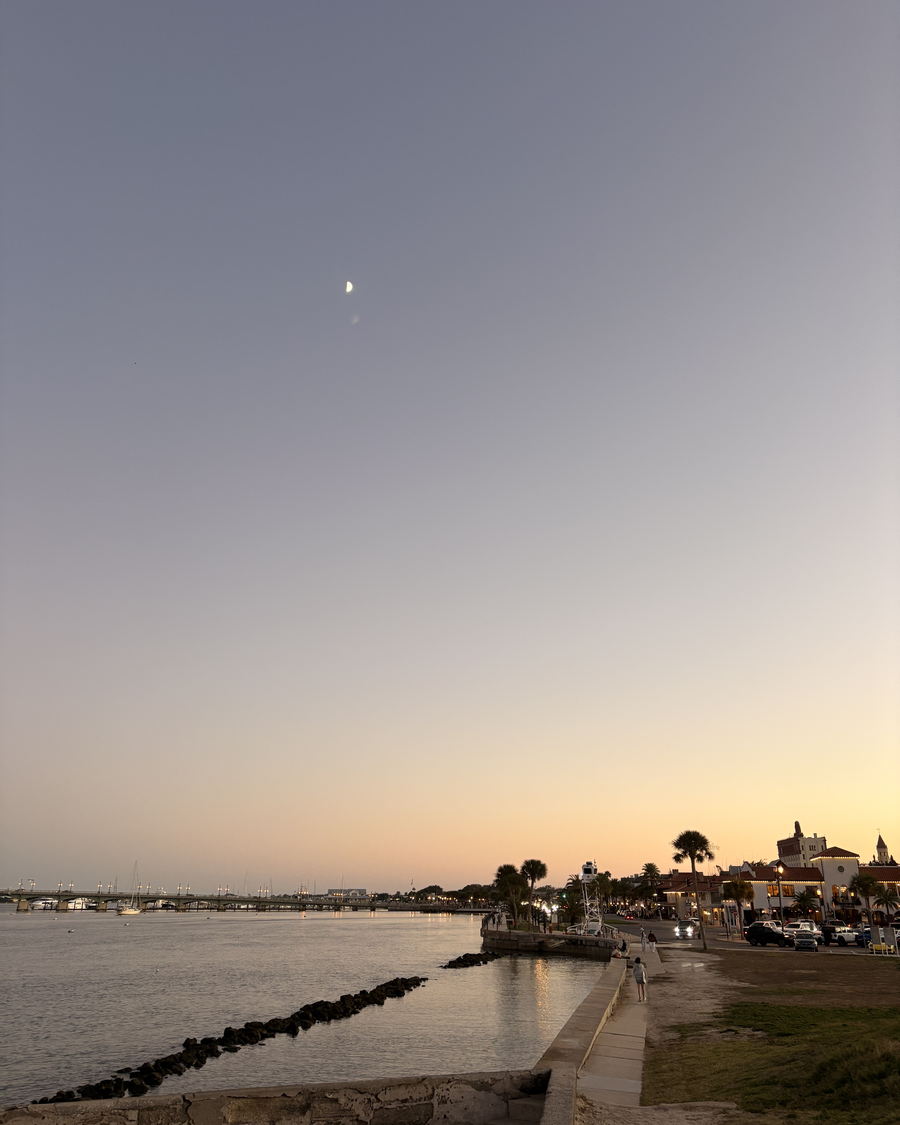 The St. Augustine bayfront at dusk with a half moon overhead